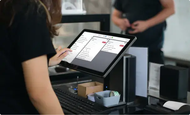 A restaurant server using a sleek tablet or touchscreen POS system at a counter
