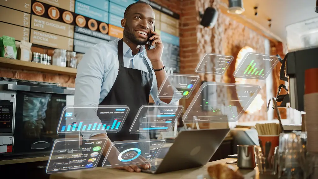 A manager overseeing operations with multiple POS terminals or dashboards on a laptop